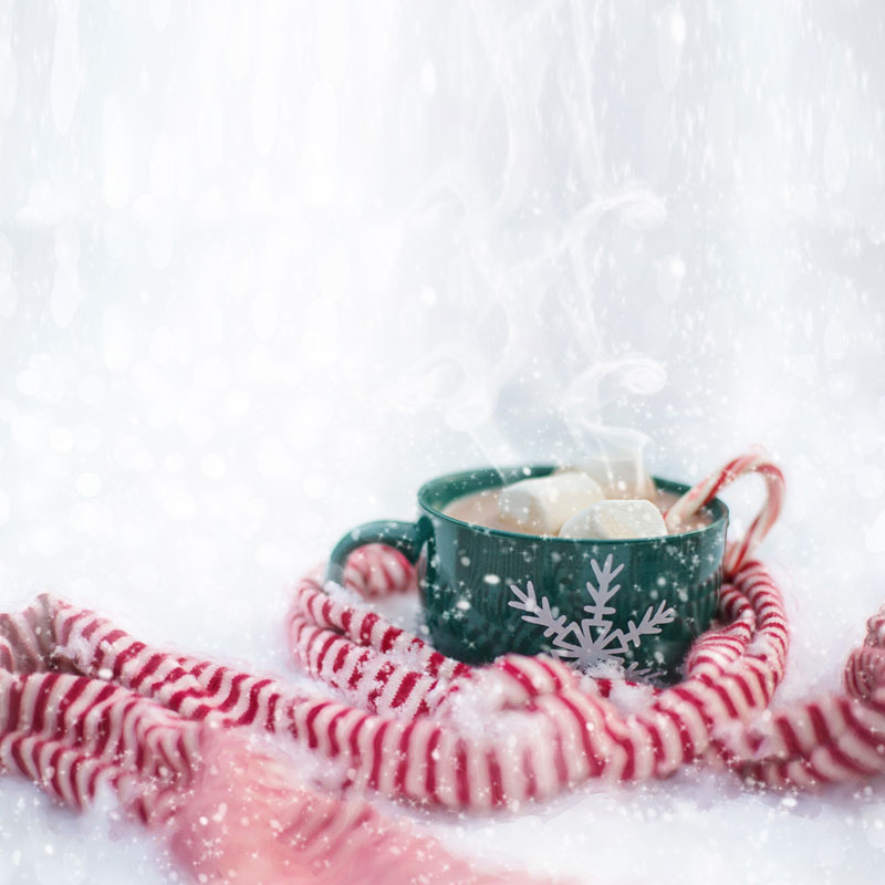 Ilustracja przedstawiająca kubek gorącej czekolady w zimowej scenerii 