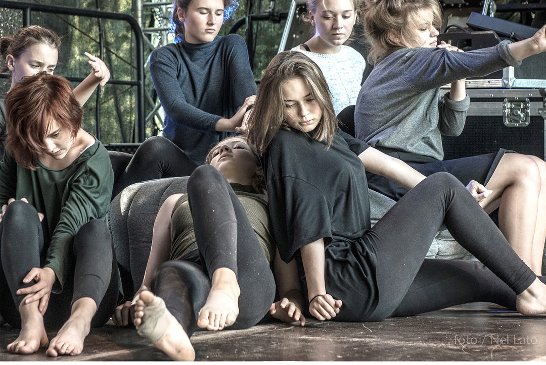 Zdjęcie promocyjne zespołu. Fot. Nel Lato Na zdjęciu grupa tancerek na scenie. Zdjęcie w trakcie tańca. Tancerki znajdują się w zwartej grupie.