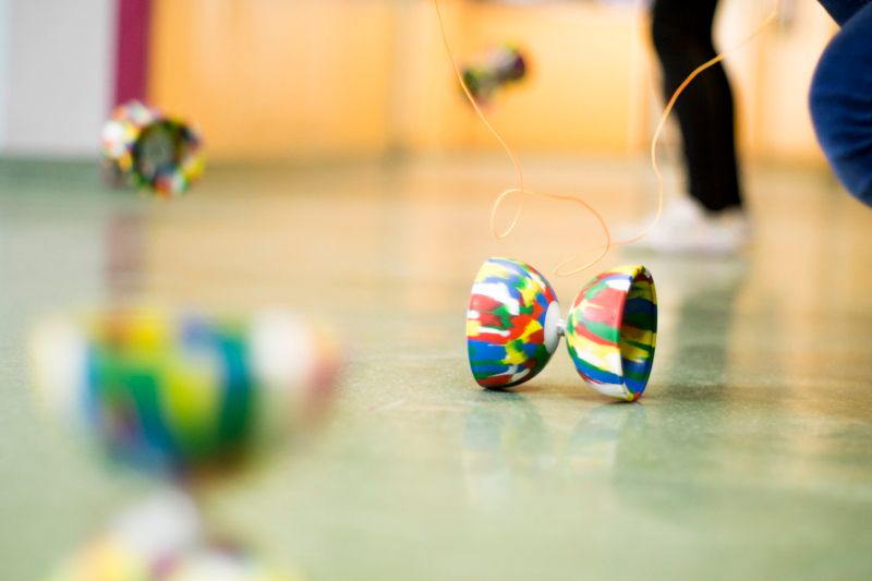 Zdjęcie przedstawia zbliżenie na narzędzia cyrkowe w czasie przeprowadzanego treningu/ warsztatów. W tle jasne tło i nogi osoby trenującej